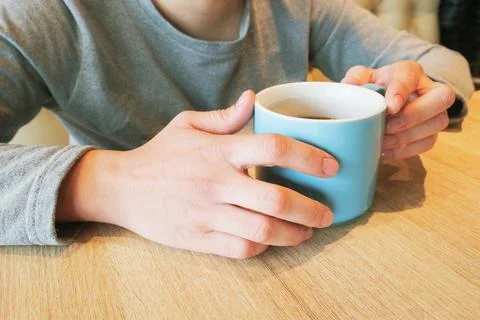 Female hands at table hold ceramic mug with black coffee. The concept of coff Stock Photos