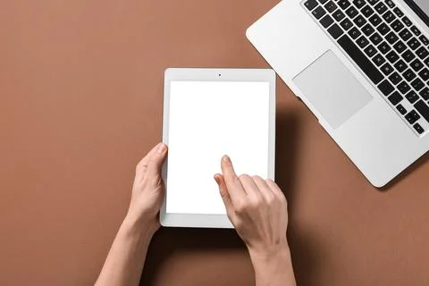 Female hands with tablet computer and laptop on brown background Stock Photos