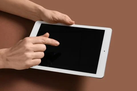 Female hands with tablet computer on brown background Stock Photos