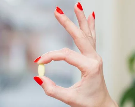 Female hands, tablet held between fingers, on bright background Stock Photos