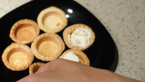 Female hands take empty tartlets from a plate and fill them with cottage cheese Stock Footage 119403607