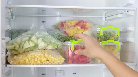Female Hands take out containers with frozen vegetables in the fridge Stock Footage 145814835