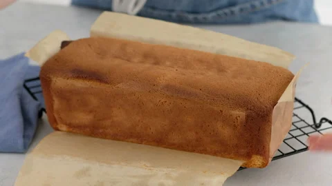 Female hands take out a rectangular sponge cake and baking paper for a cake with 스톡 동영상 146482847