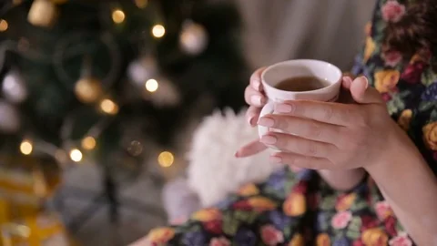 Female hands with tea cup near christmas tree. Beaty girl drinking tea Stock Footage
