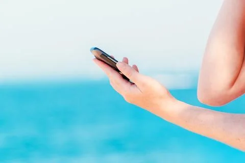Female hands texting message on mobile phone on seaside Stock Photos