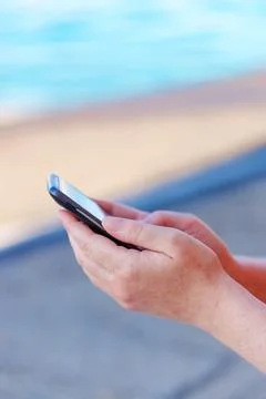 Female hands texting message on mobile phone on seaside Stock Photos
