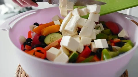 Female hands throw sliced mozzarella cheese into a plastic container with salad Video stock 169960194