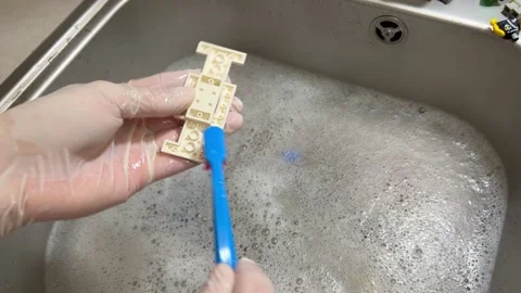 Female hands with a toothbrush clean constructor blocks. Washing detail. Stock Footage 237165692