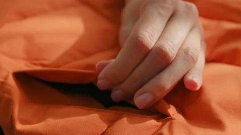 Female hands touching groping material orange waterproof fabric of winter jacket Видео 220660523