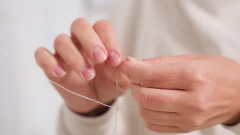 Female Hands Tying Two Strings With Calm Precision In Sewing Environment Stock Footage 307136974