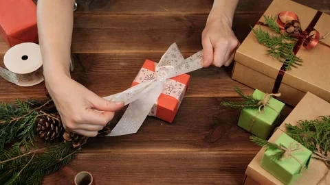 Female hands tying a white bow to a wrapped gift box for a Christmas present. Stock Footage 163620856