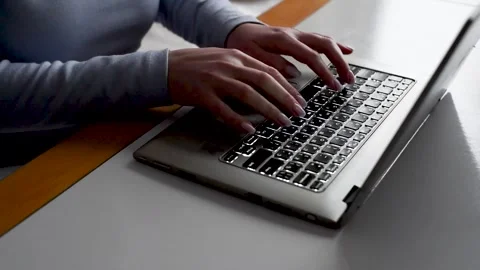 Female hands typing on the laptop computer keyboard on the table in the dark Video stock 327493707