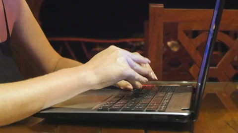 Female hands typing text on notebook keyboard in cafe at evening. Freelancer Stock Footage 302823955