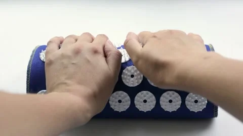 Female hands use cushion roller acupuncture applicator pad with plastic spikes Video stock 278467952