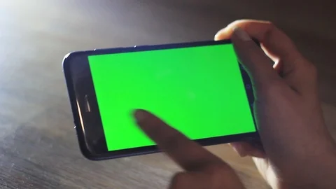 Female hands uses a mobile device with a green screen. Chroma Key Stock Footage 96985626