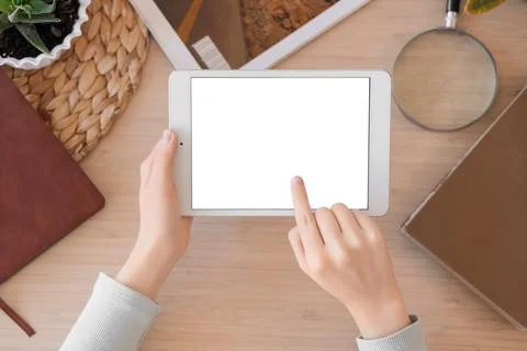 Female hands using blank tablet computer with notebooks on table, top view Stock Photos