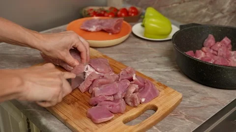 Female hands using a chefs knife to portion pork tenderloin on a cutting board Видео 316691691