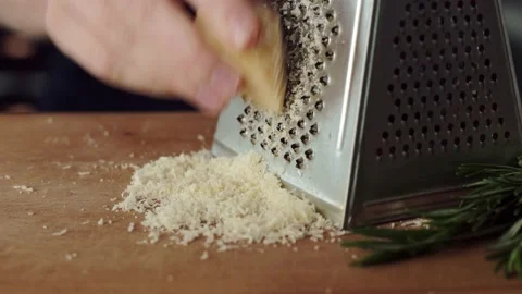 Female hands using grater for grating hard cheese. Grated cheese Stock Footage 194661883