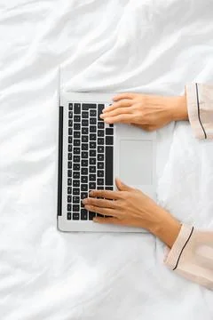 Female hands using laptop on bed in hotel room, top view Stock Photos