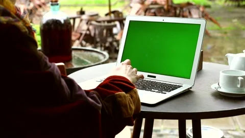 Female hands using laptop with blank green screen sitting in outdoor cafe restau Video stock 131548199