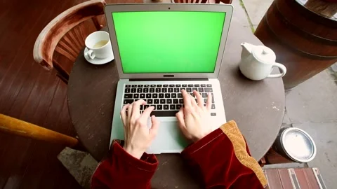 Female hands using laptop with blank green screen on wooden round table in moder Video stock 131694115