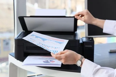 Female hands using printer on desk in office Stock Photos