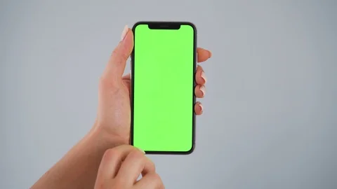 Female hands using a smartphone with a green screen on a gray background. Chroma Stock Footage 127516524