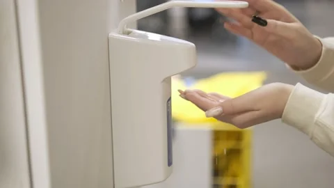 Female hands washing under an automatic alcoholic sanitizer dispensary in a Stock Footage 166897098