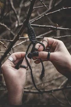 Female hands weaving a macrame braid on a tree branch Stock Photos