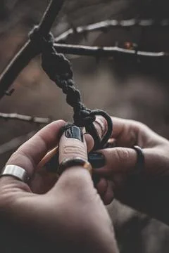 Female hands weaving a macrame braid on a tree branch Stock Photos