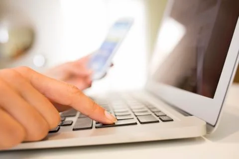 Female hands working on the computer, cell phone Stock Photos