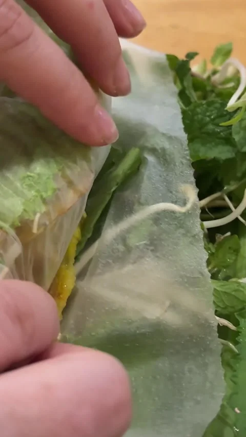 Female hands wrap Spring Roll scrambled eggs with vegetables in rice paper Stock Footage 307131961