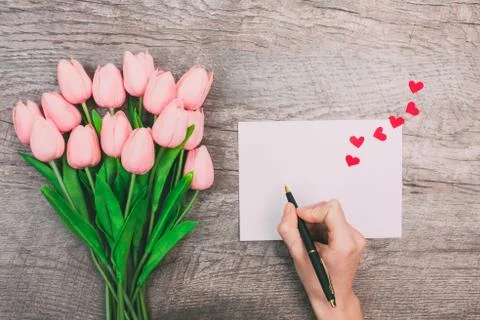 Female hands write a message of love on a white envelope, on a wooden backgro Foto stock