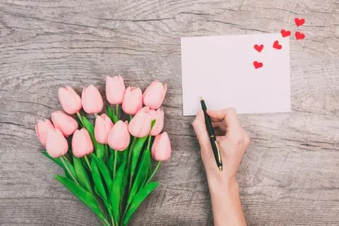 Female hands write a message of love on a white envelope, on a wooden backgro Foto stock