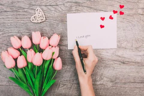 Female hands write a message of love on a white envelope, on a wooden backgro Foto stock