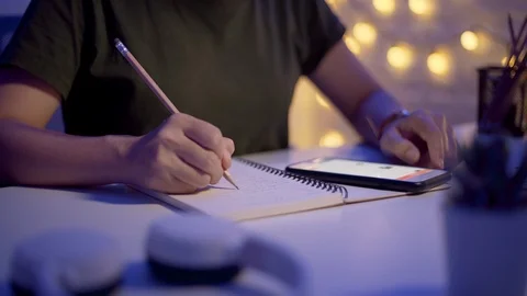 Female hands write in a notebook and using smart phone at night Stock-Footage 124628776
