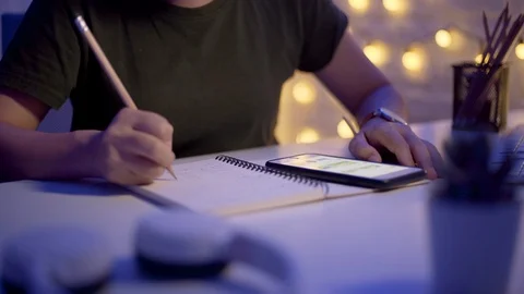 Female hands write in a notebook and using smart phone at night Stock-Footage 124628866