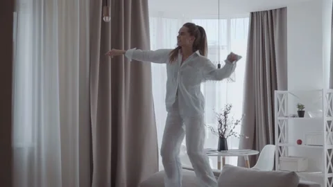 Female having fun and jumping on sofa In the interior of the apartments Stock Footage 134899042