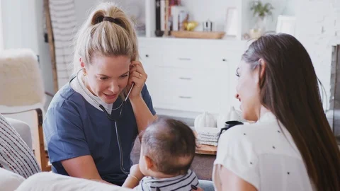 Female healthcare worker visiting young mum and her infant son at home, using Stock Footage