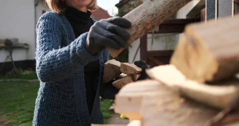 A female in her thirties creating a stack of firewood, 4k Stock Footage 142805049