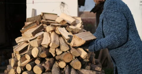 A female in her thirties creating a stack of firewood, 4k Stock Footage 142806166