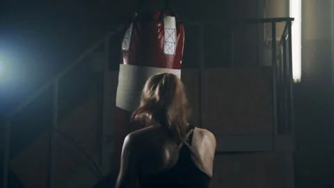 A female high-powered fighter practices her punches on a punching bag Stock Footage 273246190