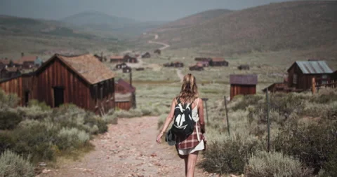 Female hiker with backpack exploring the gold mining ghost town of Bodie, CA Stock Footage 167337244