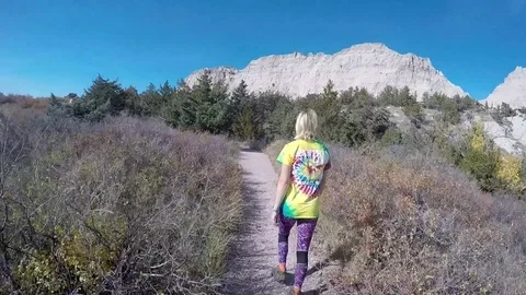 Female Hikes through a Juniper forest in the Badlands National Park: V2 Stock Footage 81764287