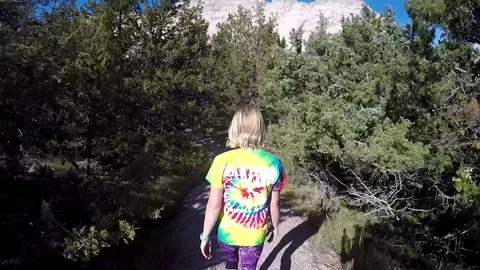 Female Hikes through a Juniper forest in the Badlands National Park: V1 Stock Footage 81765130