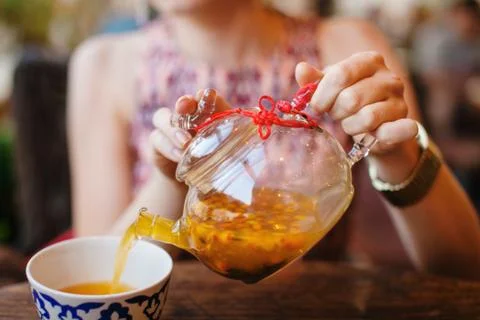 Female Hnds Pouring Sea Buckthorn Tea in Glass Kettle Stock Photos