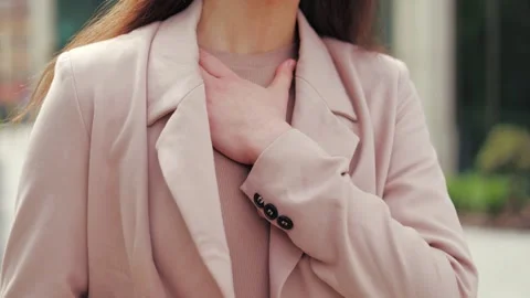 Female holding phone while touching chest because having respiratory problems Video stock 275829678