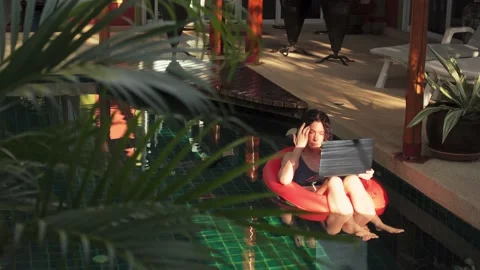 Female holiday maker is floating in open swimming pool on rubber ring with Stock Footage 226836530