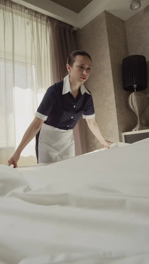 Female Housekeeper Spreading Clean Sheet While Making Bed in Hotel Room Stock Footage 342924092