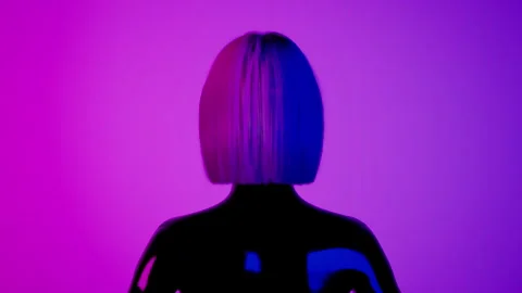 Female hyper-realistic robot or cyborg turn around in studio with neon light Stockbeeldmateriaal 243900335